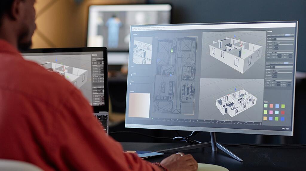 Persoon aan bureau werkt op computer met 3D-ontwerpsoftware.