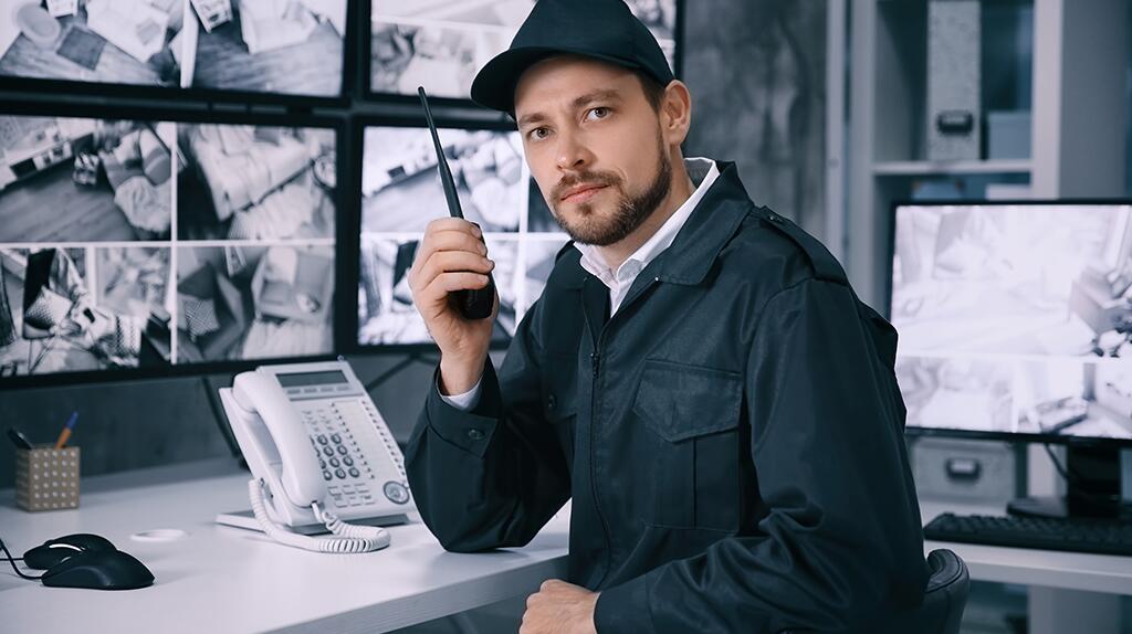 Beveiliger met portofoon in controlekamer.