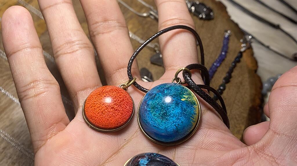 Twee hangers, oranje en blauw, rustend op een hand.