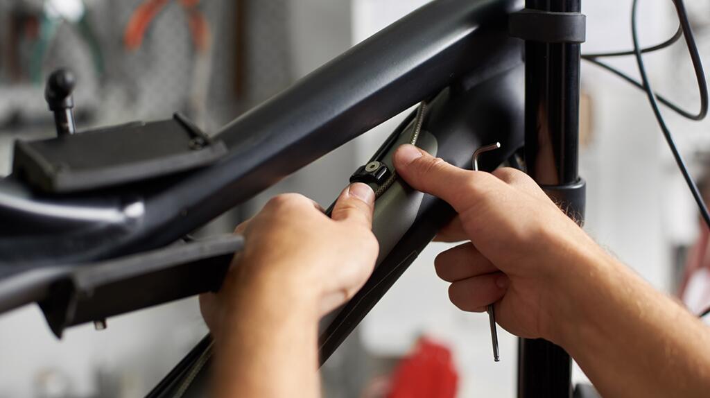 Fietsenmaker stelt ketting van een fiets af in een werkplaats.