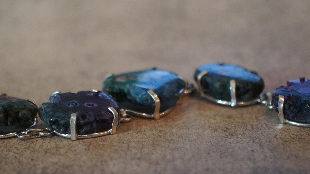 Ketting met blauwe en paarse edelstenen op een bruine achtergrond.