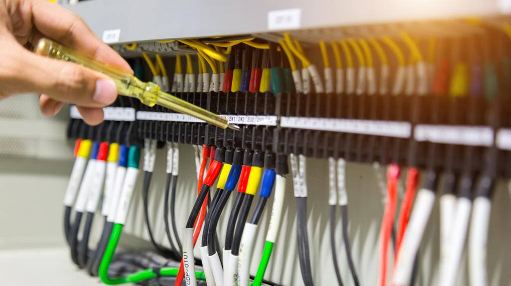 Elektricien controleert bedrading met tester in schakelkast.