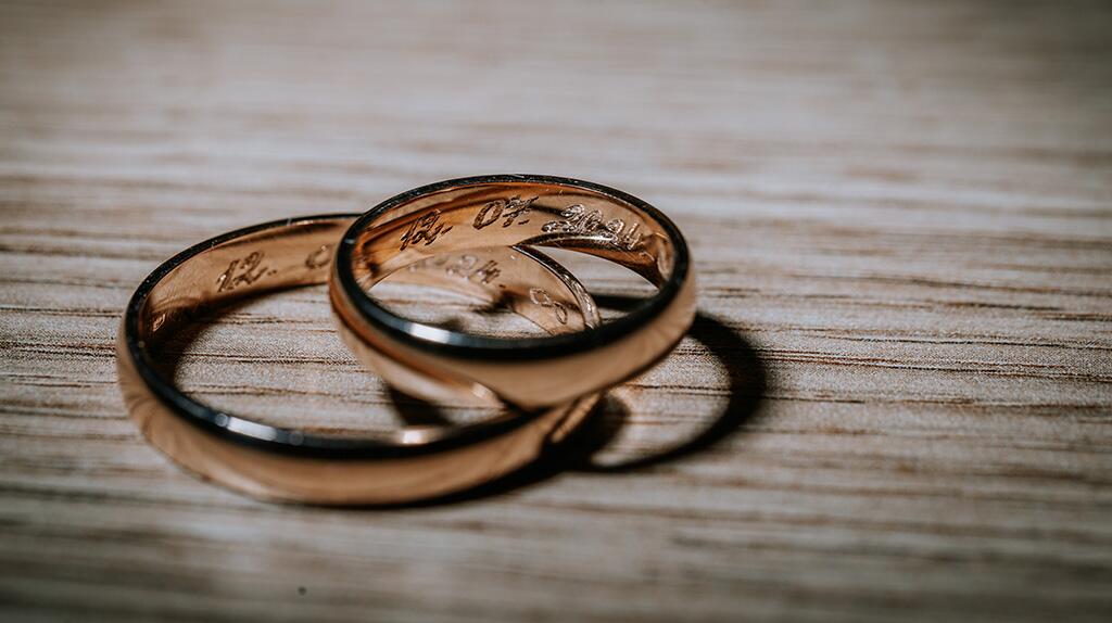 Twee gouden trouwringen op een houten oppervlak.