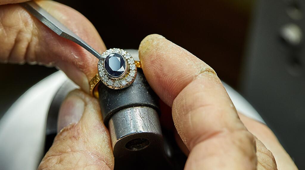 Sieradenmaker bewerkt een ring met een gereedschap.