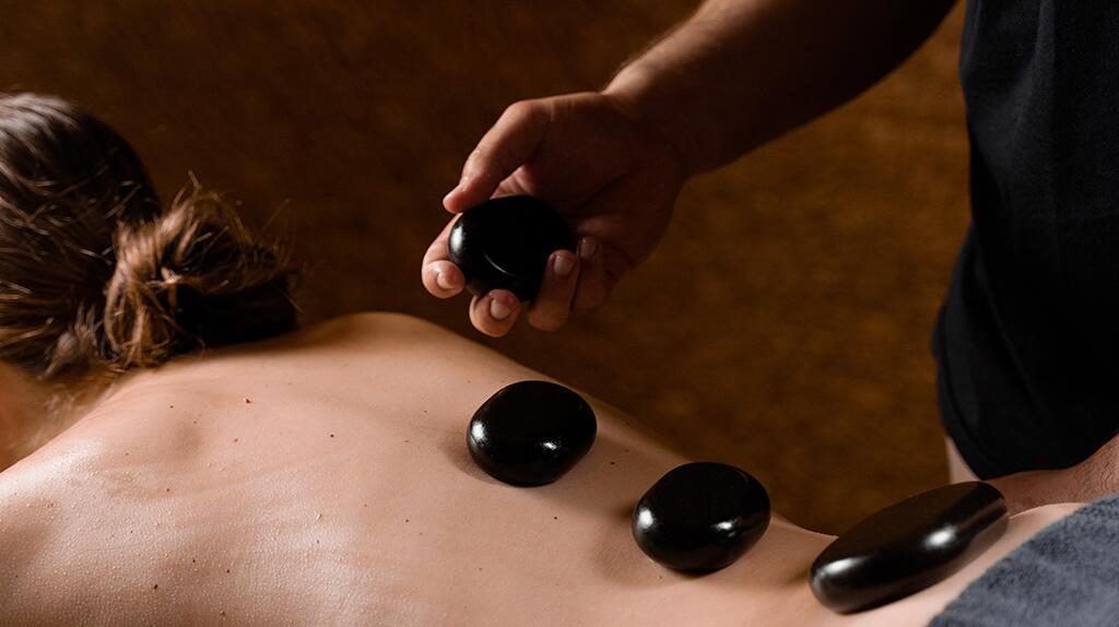 Rugmassage met warme stenen op rug van een persoon.