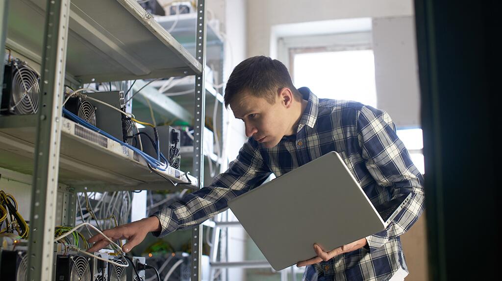 Jonge man controleert serverrekken met een laptop.