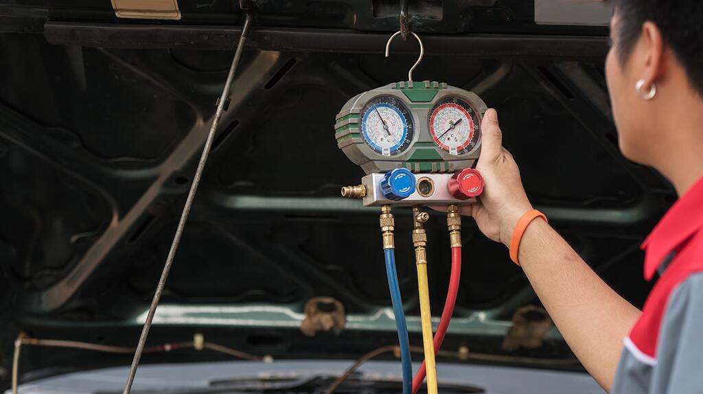 Monteur controleert drukmeter bij auto-onderhoud.