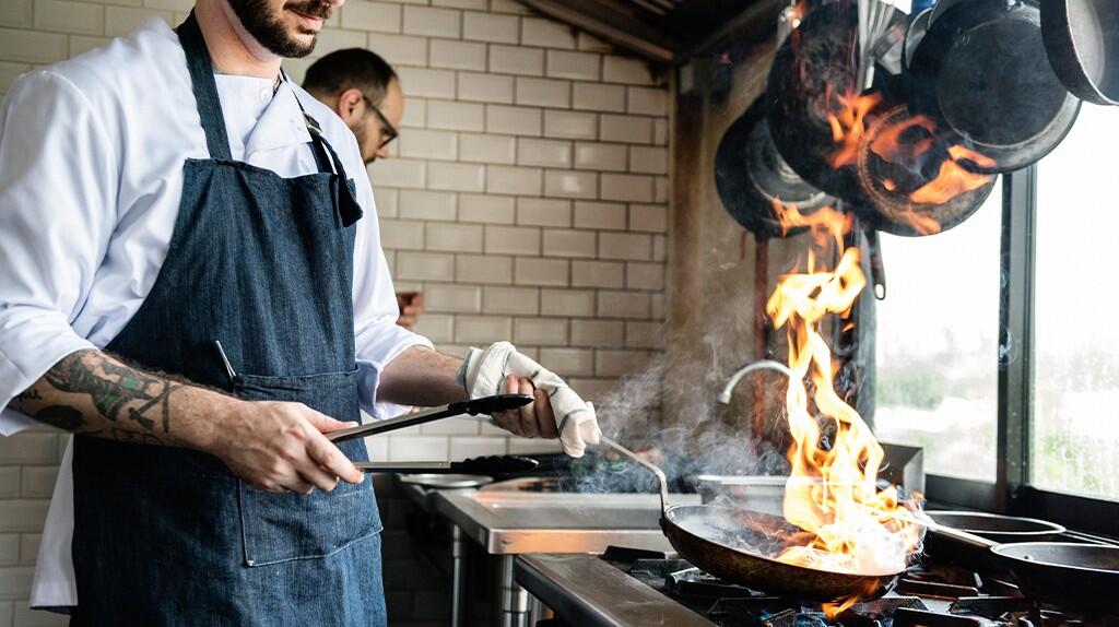 Chef bakt met hoog vuur in een professionele keuken.
