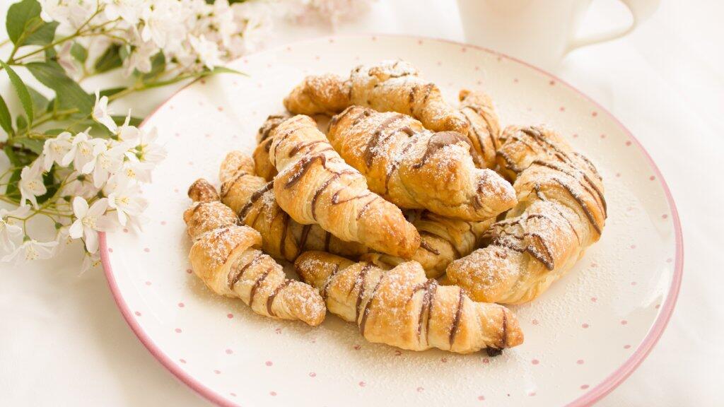 Croissants op een bord met bloemen op de achtergrond.