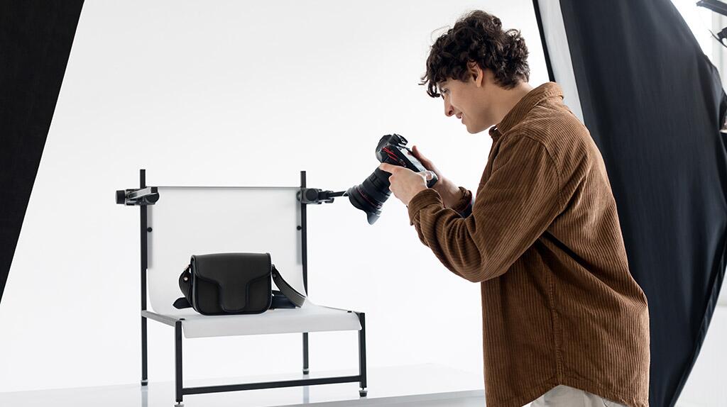 Persoon fotografeert zwarte tas in studio.