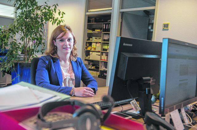 Vrouw aan bureau met computer en planten, kantooromgeving.
