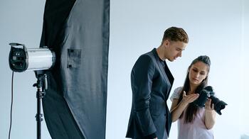 Fotograaf met camera en man in studio met lichtopstelling.