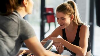 Twee vrouwen praten en lachen in de sportschool.