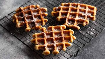 Drie krokante wafels op een zwart afkoelrek.