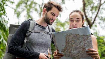 Twee wandelaars kijken naar een kaart in een bosrijke omgeving.