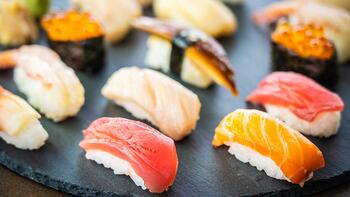 Assortiment van kleurrijke sushi op een donkere schaal.