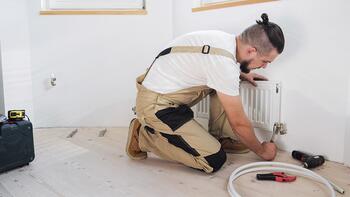Monteur repareert radiator in lichte kamer.