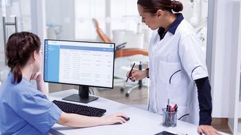 Twee medisch professionals bespreken gegevens op een computerscherm in een kliniek.