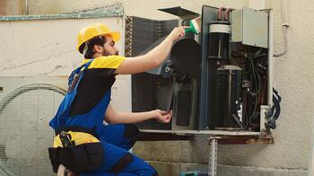 Monteur in overall repareert airconditioner buiten.