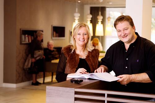Man en vrouw glimlachen bij een balie in een moderne lobby.