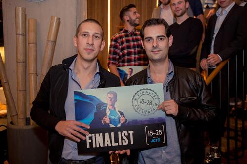 Twee mannen met "Finalist" bord poseren op een evenement.