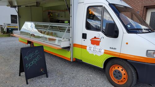 Marktwagen met open zijpaneel en schoolbordmenu ervoor.