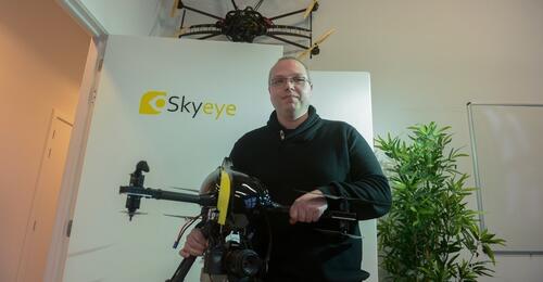 Persoon met drone naast planten in kantoorruimte.