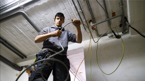 Elektricien werkt aan bedrading aan plafond.