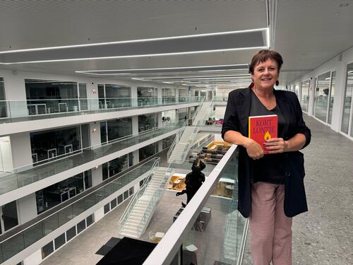 Vrouw in moderne kantoorgebouw met boek in handen.