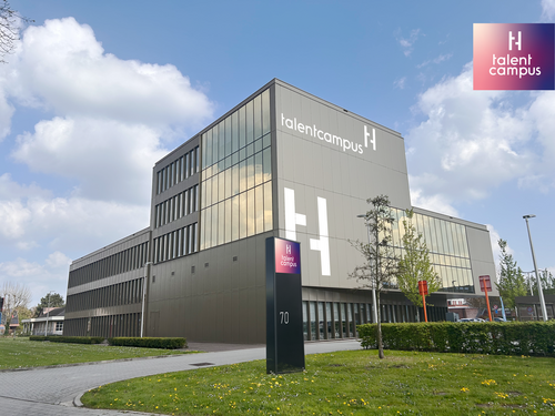 Modern gebouw met glas en staal, helderblauwe lucht, logo rechtsonder.