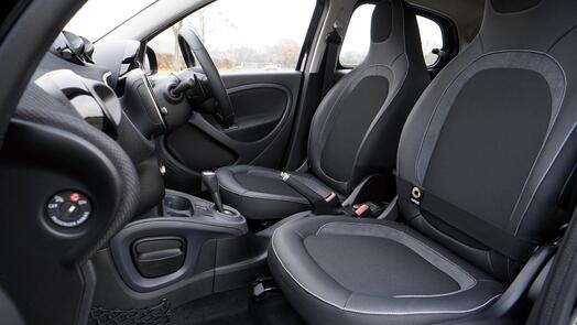Interieur van een auto met zwarte lederen stoelen en een stuurwiel.