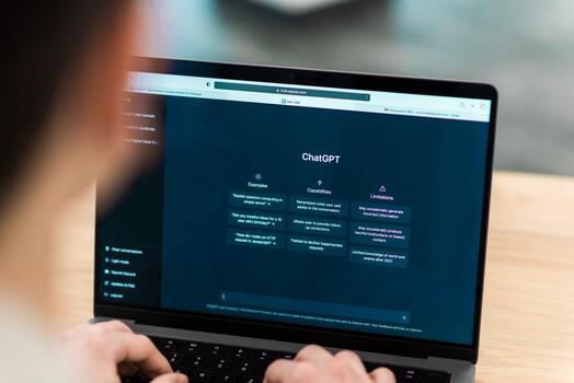 Iemand typt op een laptop met ChatGPT open op het scherm.