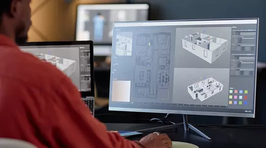 Man ontwerpt gebouwmodellen op computers in moderne kantooromgeving.