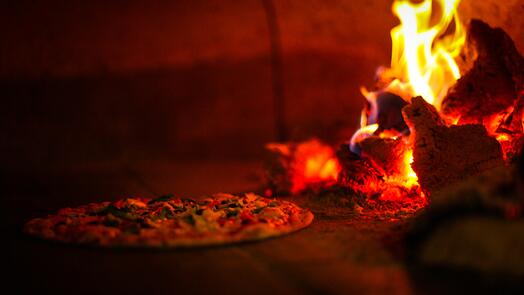 Pizza in houtoven met vlammen rechts.