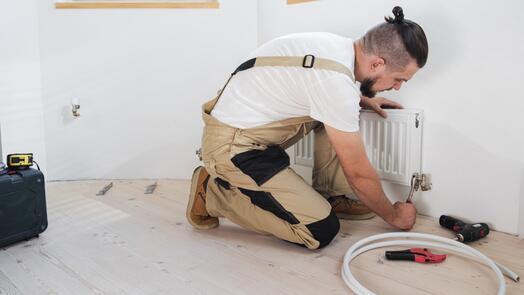 Monteur in overall repareert een radiator.
