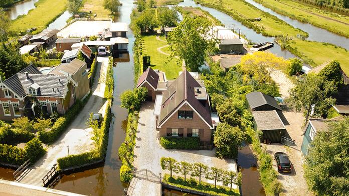 Luchtfoto van huizen aan kanalen in een groene, landelijke omgeving.