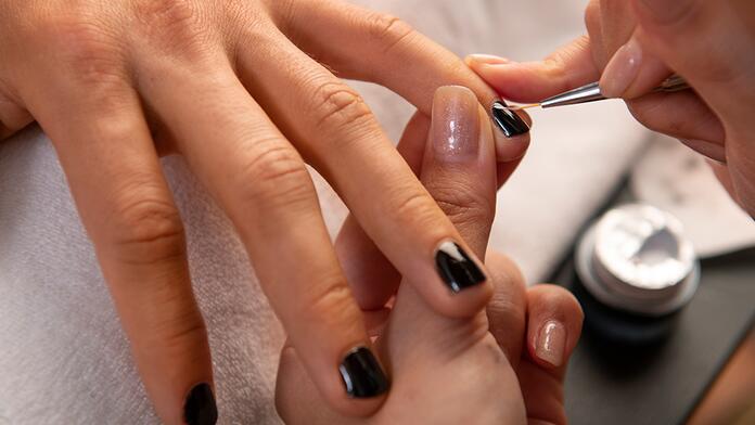 Nagels worden gelakt met zwarte nagellak.