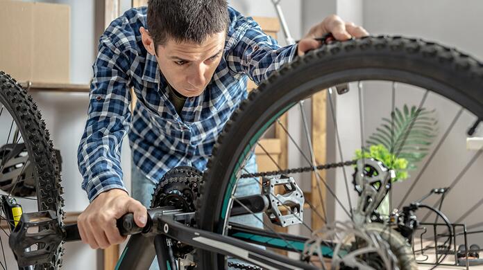 Man repareert fiets in werkplaats.