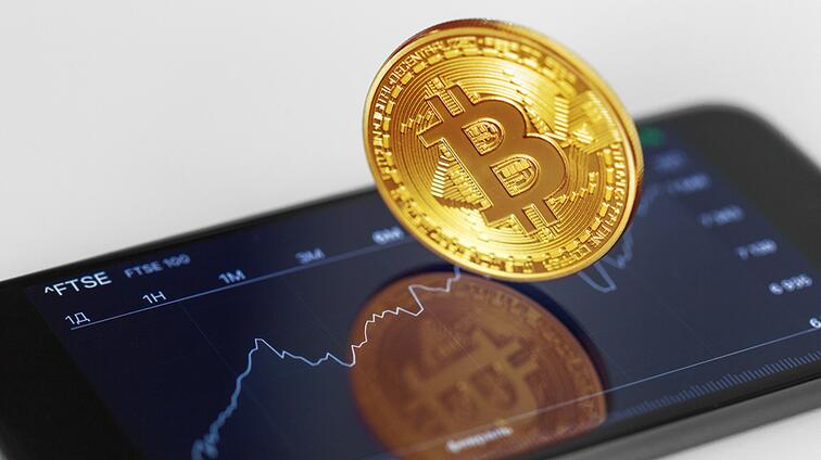 Gouden bitcoin zweeft boven smartphone met koersgrafiek.