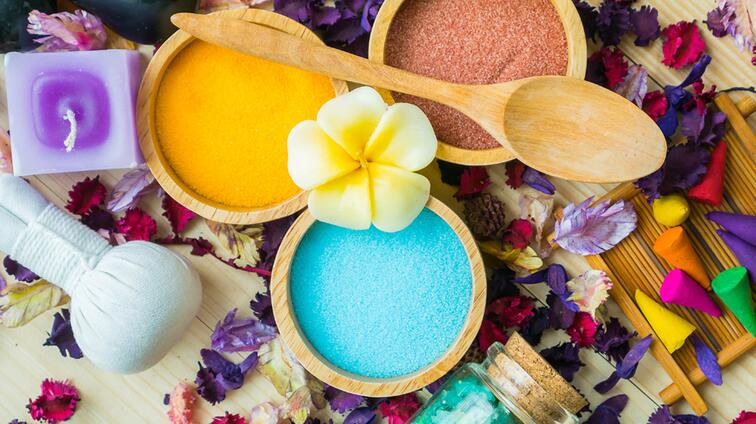 Vrolijke spa setting met kleurrijke zand en bloemaccenten.