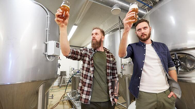 Twee mannen inspecteren bier in een brouwerij.