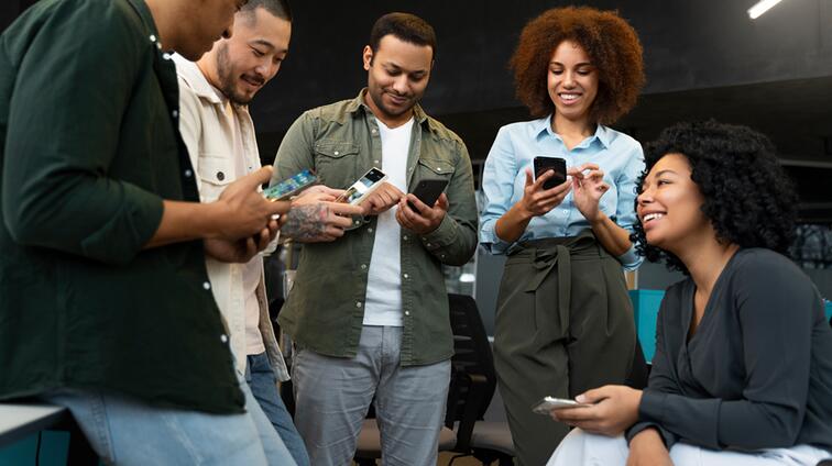 Mensen in informele kleding lachen en kijken naar hun telefoons.