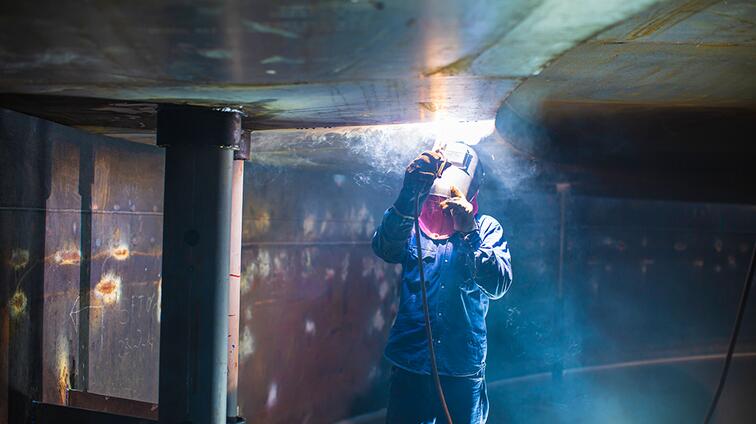 Werker last metalen plaat in donkere werkplaats.