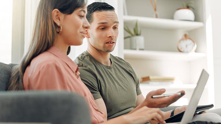 Twee mensen overleggen op de bank met een laptop.