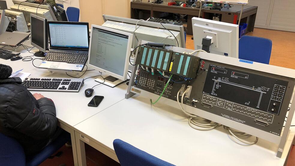 Computerruimte met bureaus, laptops en een ouderwetse console.